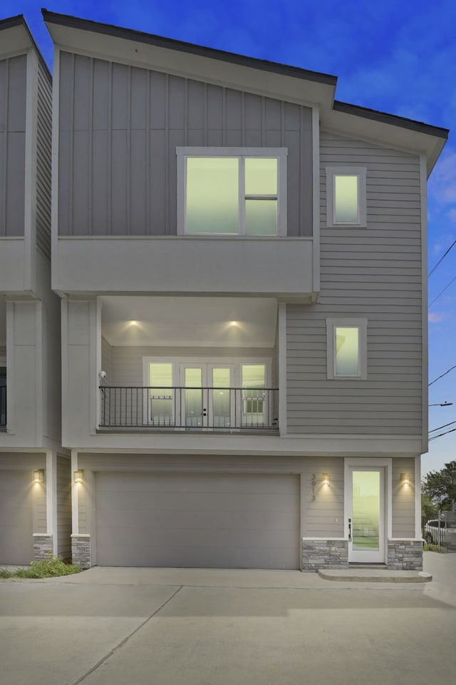 3913 Hare St, Houston, TX 77020 - view of front facade featuring stone siding, a garage, board and batten siding, and driveway