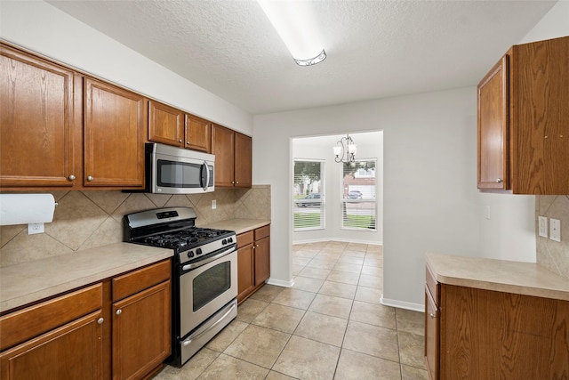4838 Fair Oak Dale Ln, Humble, TX 77346 - kitchen with appliances with stainless steel finishes, brown cabinetry, tasteful backsplash, light countertops, and a textured ceiling
