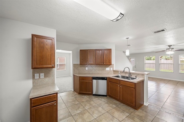 4838 Fair Oak Dale Ln, Humble, TX 77346 - kitchen featuring stainless steel dishwasher, a textured ceiling, brown cabinets, a peninsula, and light countertops