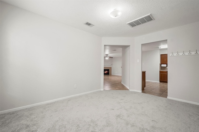 4838 Fair Oak Dale Ln, Humble, TX 77346 - empty room with light tile patterned floors, light colored carpet, a textured ceiling, and a ceiling fan
