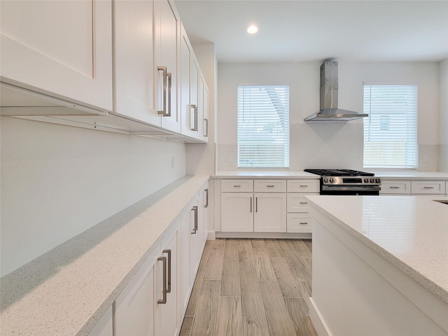 6735 Cohn St, Houston, TX 77091 - kitchen featuring wall chimney exhaust hood, stainless steel range, white cabinets, healthy amount of natural light, and recessed lighting