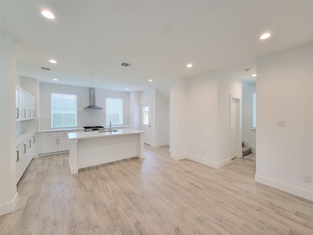 6735 Cohn St, Houston, TX 77091 - kitchen featuring wall chimney range hood, light wood finished floors, light countertops, white cabinetry, and recessed lighting