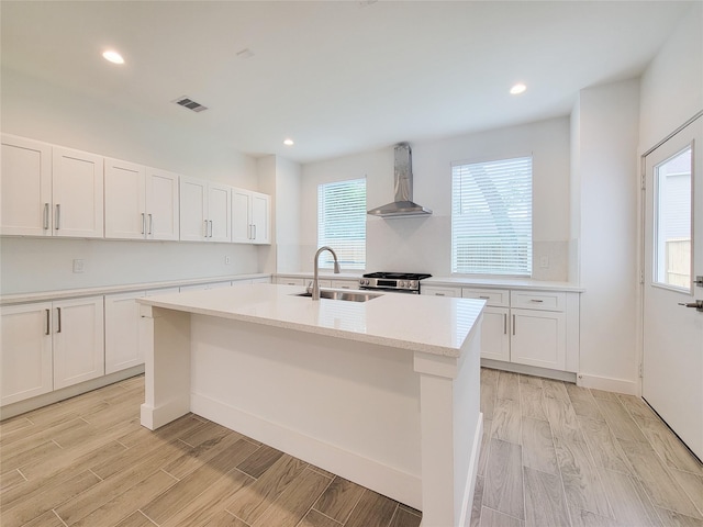 6735 Cohn St, Houston, TX 77091 - kitchen with wall chimney exhaust hood, stainless steel range oven, a center island with sink, light wood-type flooring, and recessed lighting