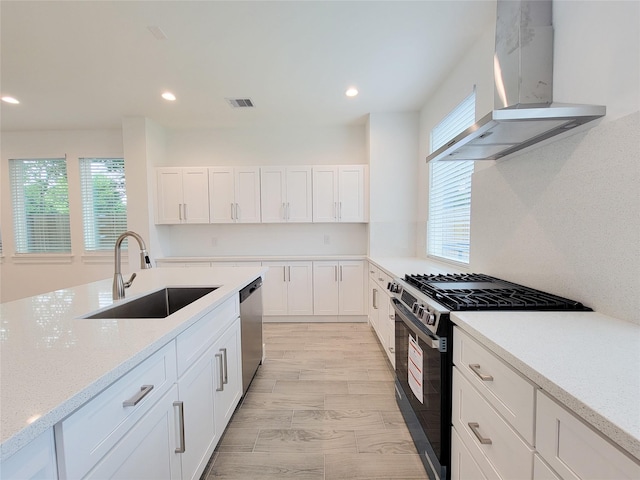 6735 Cohn St, Houston, TX 77091 - kitchen with wall chimney range hood, stainless steel appliances, recessed lighting, white cabinets, and light stone counters