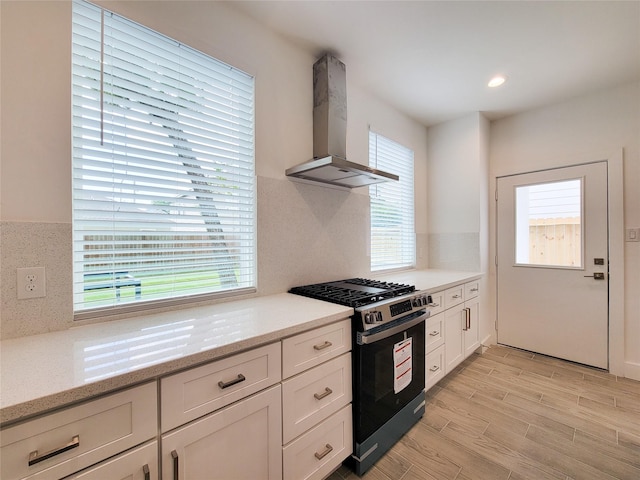 6735 Cohn St, Houston, TX 77091 - kitchen with ventilation hood, gas range, white cabinets, light wood-type flooring, and light stone counters