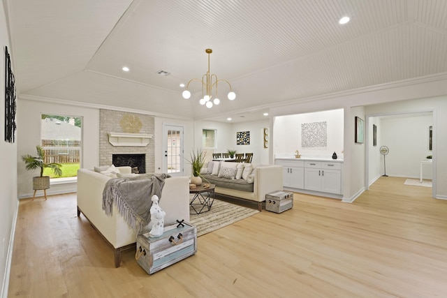 3351 S Sutton Sq, Stafford, TX 77477 - living room with vaulted ceiling, light wood-style flooring, a brick fireplace, a chandelier, and crown molding