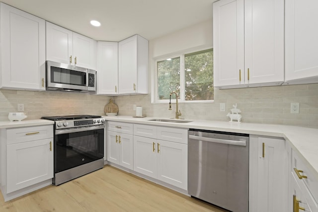 3351 S Sutton Sq, Stafford, TX 77477 - kitchen with appliances with stainless steel finishes, white cabinets, light wood-style floors, light countertops, and decorative backsplash