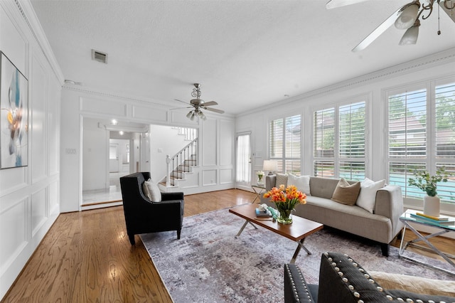 20234 Brondesbury Dr, Katy, TX 77450 - living room with a decorative wall, ceiling fan, ornamental molding, wood finished floors, and stairs