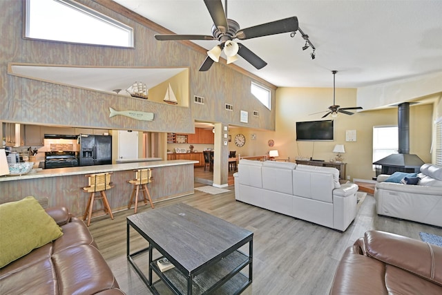 206 Galleon Dr, Freeport, TX 77541 - living room featuring a ceiling fan, light wood finished floors, rail lighting, a wood stove, and a high ceiling