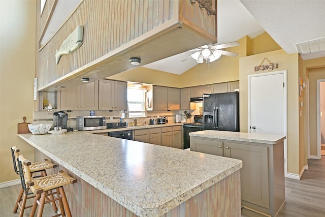 206 Galleon Dr, Freeport, TX 77541 - kitchen with black appliances, a peninsula, light wood-style floors, high vaulted ceiling, and light countertops