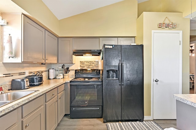 206 Galleon Dr, Freeport, TX 77541 - kitchen featuring black appliances, under cabinet range hood, lofted ceiling, light wood-type flooring, and tasteful backsplash