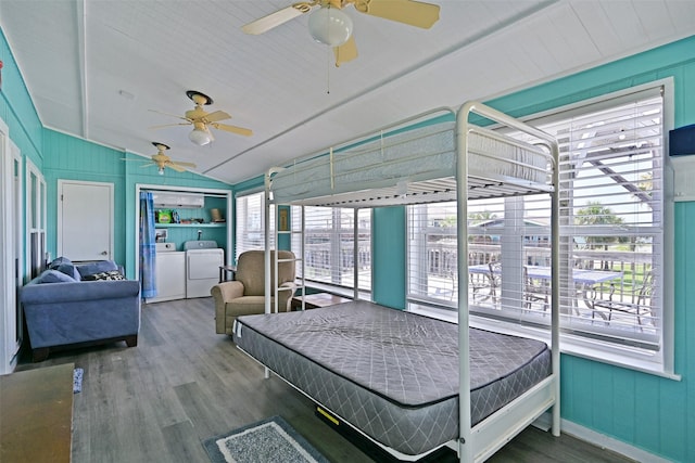 206 Galleon Dr, Freeport, TX 77541 - bedroom featuring washing machine and clothes dryer, vaulted ceiling, wood finished floors, and wooden walls