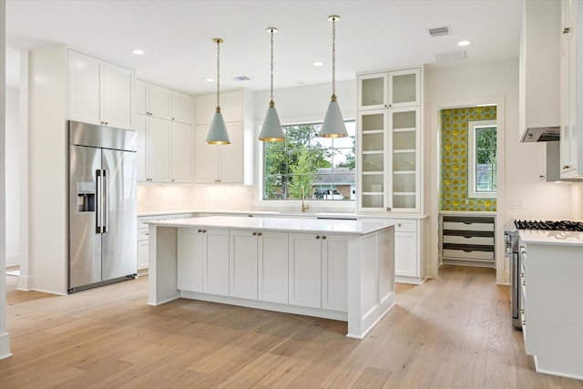 2006 Chantilly Ln, Houston, TX 77018 - kitchen featuring stainless steel appliances, light wood-style floors, white cabinetry, a center island, and light countertops