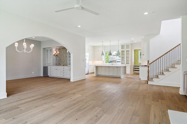2006 Chantilly Ln, Houston, TX 77018 - unfurnished living room featuring a chandelier, light wood finished floors, arched walkways, ceiling fan, and stairway