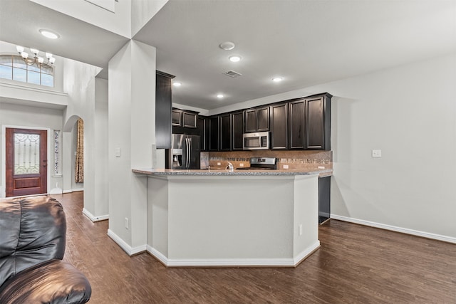 18514 Providence Landing Ln, Richmond, TX 77407 - kitchen with appliances with stainless steel finishes, dark wood finished floors, arched walkways, a chandelier, and recessed lighting