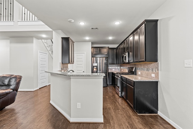18514 Providence Landing Ln, Richmond, TX 77407 - kitchen featuring appliances with stainless steel finishes, light stone countertops, decorative backsplash, dark wood-style flooring, and recessed lighting