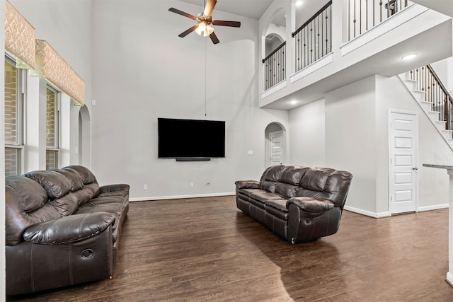 18514 Providence Landing Ln, Richmond, TX 77407 - living area with arched walkways, a high ceiling, a ceiling fan, wood finished floors, and stairs
