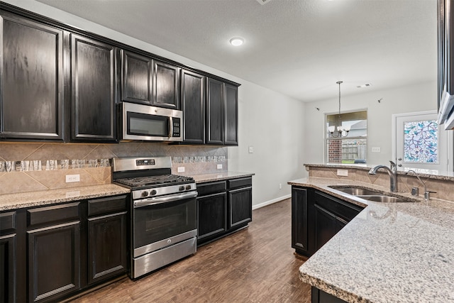 18514 Providence Landing Ln, Richmond, TX 77407 - kitchen with appliances with stainless steel finishes, decorative backsplash, dark wood-style floors, hanging light fixtures, and light stone countertops