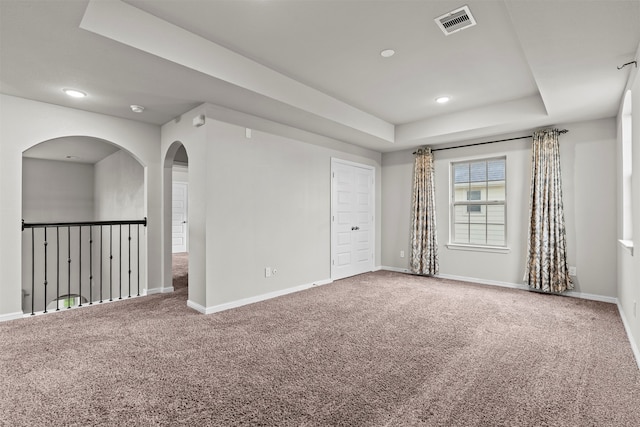 18514 Providence Landing Ln, Richmond, TX 77407 - spare room featuring a tray ceiling, carpet, recessed lighting, and arched walkways