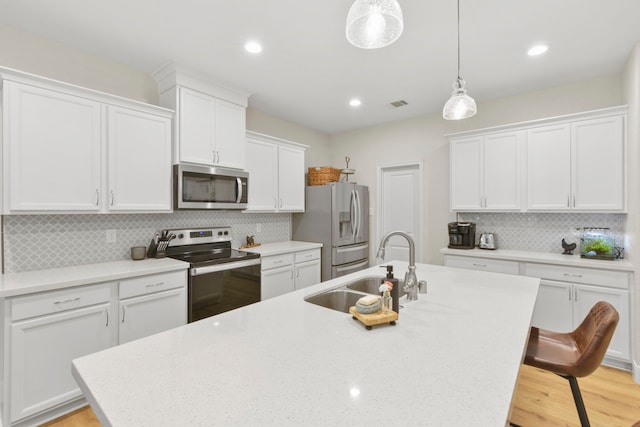 16003 Westward Ho St, Stagecoach, TX 77355 - kitchen featuring appliances with stainless steel finishes, an island with sink, white cabinets, a breakfast bar area, and recessed lighting