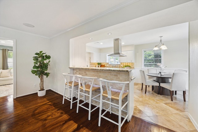 9222 Bronco Dr, Houston, TX 77055 - kitchen featuring island exhaust hood, white cabinets, tasteful backsplash, wood finished floors, and crown molding