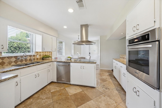 9222 Bronco Dr, Houston, TX 77055 - kitchen with appliances with stainless steel finishes, wall chimney range hood, backsplash, a peninsula, and white cabinetry