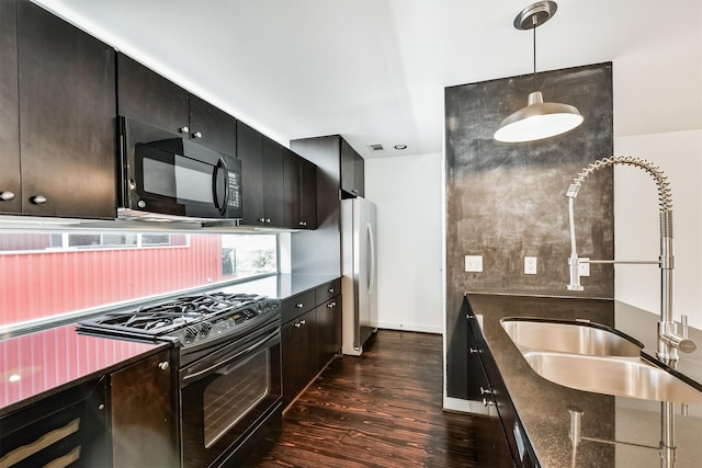 3028 Commerce St, Houston, TX 77003 - kitchen featuring black appliances, dark wood-style floors, dark cabinets, decorative light fixtures, and dark stone counters