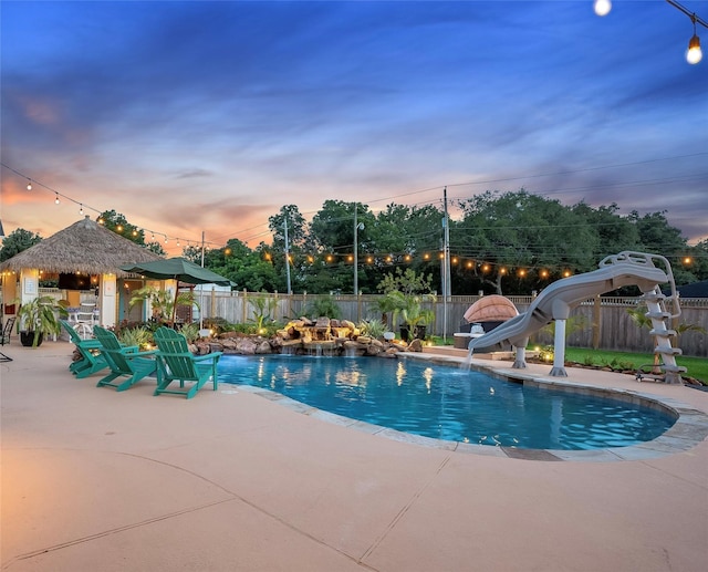 1201 Coryell St, League City, TX 77573 - pool at dusk with a patio, a fenced backyard, and a water slide