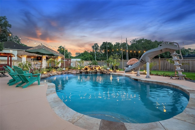 1201 Coryell St, League City, TX 77573 - pool at dusk with a fenced backyard, a water slide, and a patio area