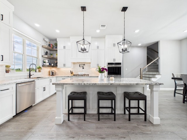 2711 Oakwood Shores Dr, Richwood, TX 77515 - kitchen featuring appliances with stainless steel finishes, a chandelier, a center island, decorative backsplash, and recessed lighting