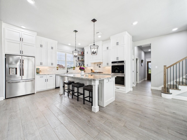 2711 Oakwood Shores Dr, Richwood, TX 77515 - kitchen with appliances with stainless steel finishes, light wood-type flooring, tasteful backsplash, a kitchen island, and a kitchen bar