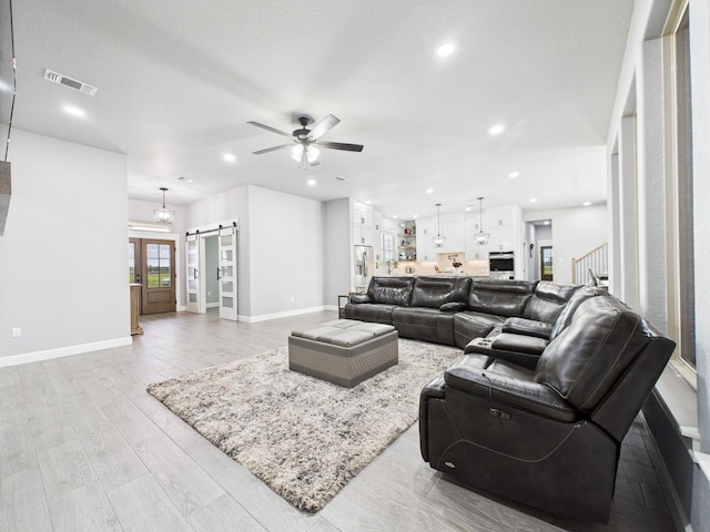 2711 Oakwood Shores Dr, Richwood, TX 77515 - living room with a barn door, ceiling fan, stairway, light wood-type flooring, and recessed lighting