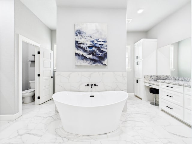 2711 Oakwood Shores Dr, Richwood, TX 77515 - bathroom with marble look tiles, vanity, tile walls, a freestanding bath, and a wainscoted wall