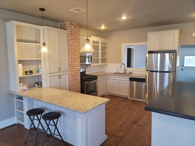 2301 45th St, Galveston, TX 77551 - kitchen featuring appliances with stainless steel finishes, open shelves, a peninsula, dark wood finished floors, and white cabinets