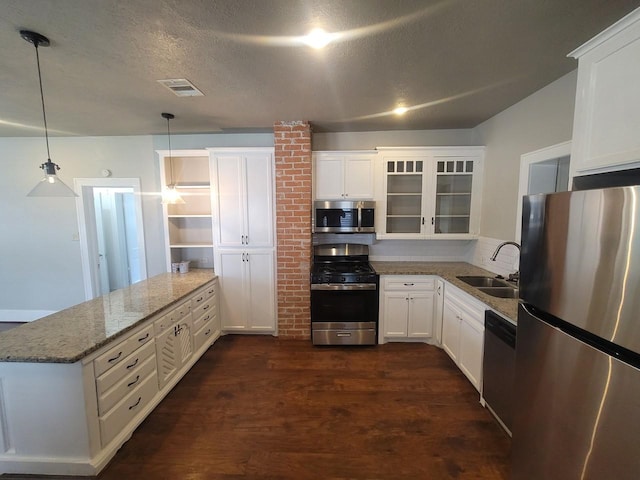 2301 45th St, Galveston, TX 77551 - kitchen with appliances with stainless steel finishes, a peninsula, dark wood-style floors, glass insert cabinets, and white cabinetry