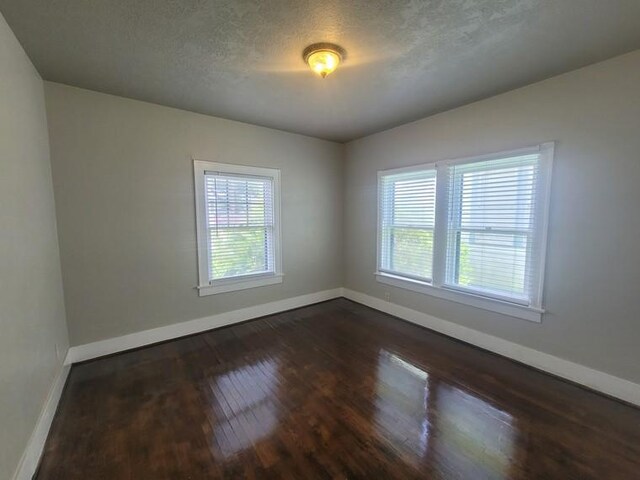 2301 45th St, Galveston, TX 77551 - spare room featuring dark wood finished floors and a textured ceiling