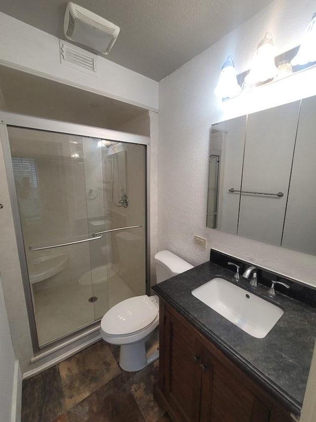 2301 45th St, Galveston, TX 77551 - bathroom featuring a shower stall, vanity, a textured wall, a textured ceiling, and stone finish flooring