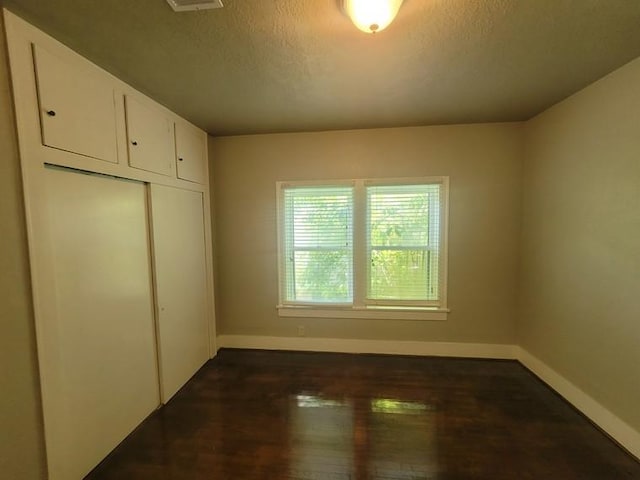 2301 45th St, Galveston, TX 77551 - unfurnished bedroom with a closet, a textured ceiling, and dark wood-type flooring