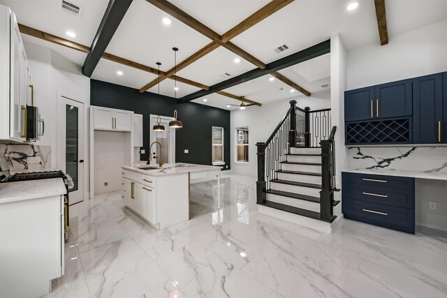 613 Melbourne St, Houston, TX 77022 - kitchen with beam ceiling, a kitchen island with sink, light stone counters, coffered ceiling, and pendant lighting
