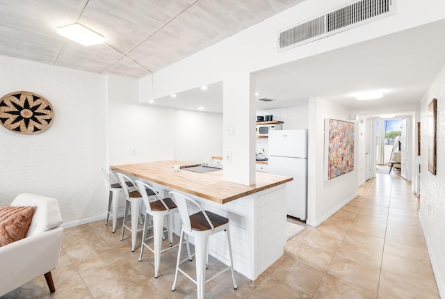 14401 Commodores Dr Unit 104, Corpus Christi, TX 78418 - kitchen with wood counters, white appliances, a kitchen breakfast bar, a peninsula, and light tile patterned floors