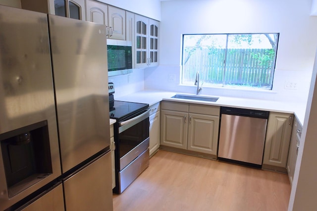12227 Gun Oak Pl, The Woodlands, TX 77380 - kitchen with stainless steel appliances, light wood-style flooring, decorative backsplash, and glass insert cabinets