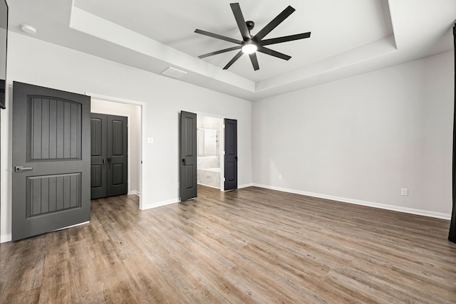 11323 Cora Ln, Willis, TX 77318 - unfurnished bedroom with a raised ceiling, wood finished floors, connected bathroom, and ceiling fan
