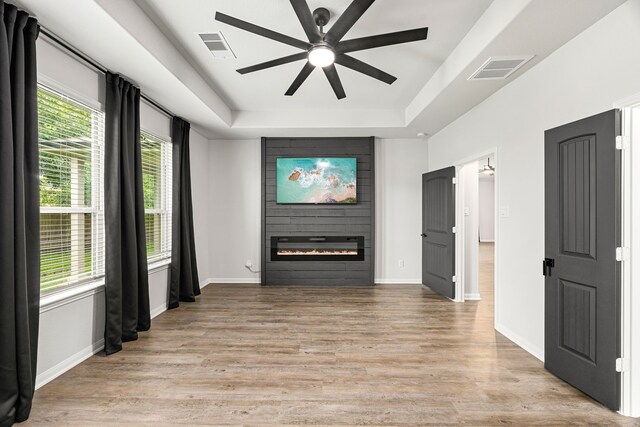 11323 Cora Ln, Willis, TX 77318 - unfurnished living room with ceiling fan, a large fireplace, light wood finished floors, and a raised ceiling