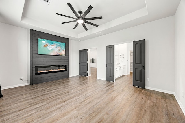 11323 Cora Ln, Willis, TX 77318 - unfurnished living room with a raised ceiling, ceiling fan, wood finished floors, and a fireplace