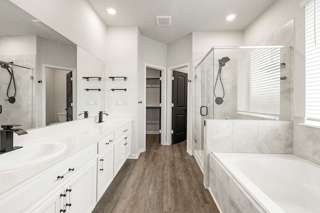 11323 Cora Ln, Willis, TX 77318 - bathroom with a bath, a stall shower, double vanity, wood finished floors, and a spacious closet