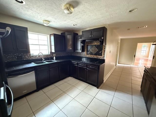 5914 Foresthaven Dr, Houston, TX 77066 - kitchen featuring stainless steel dishwasher, healthy amount of natural light, tasteful backsplash, dark countertops, and a textured ceiling
