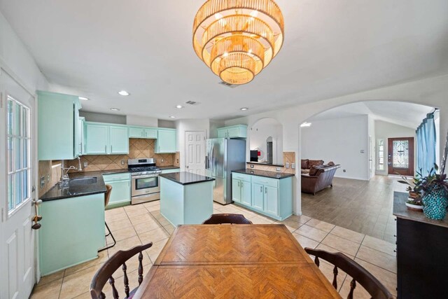10919 Barker View Dr, Cypress, TX 77433 - kitchen featuring appliances with stainless steel finishes, arched walkways, dark countertops, backsplash, and light tile patterned floors
