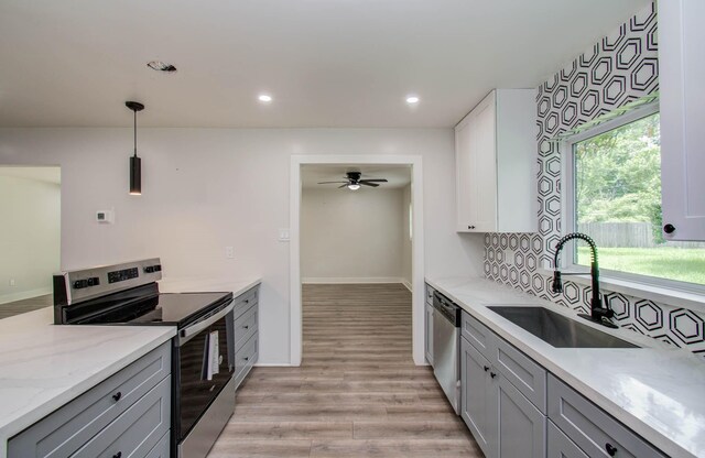 10415 Westray St, Houston, TX 77043 - kitchen with stainless steel appliances, gray cabinets, light wood finished floors, light stone counters, and hanging light fixtures