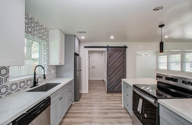 10415 Westray St, Houston, TX 77043 - kitchen featuring appliances with stainless steel finishes, a barn door, light wood-type flooring, plenty of natural light, and recessed lighting