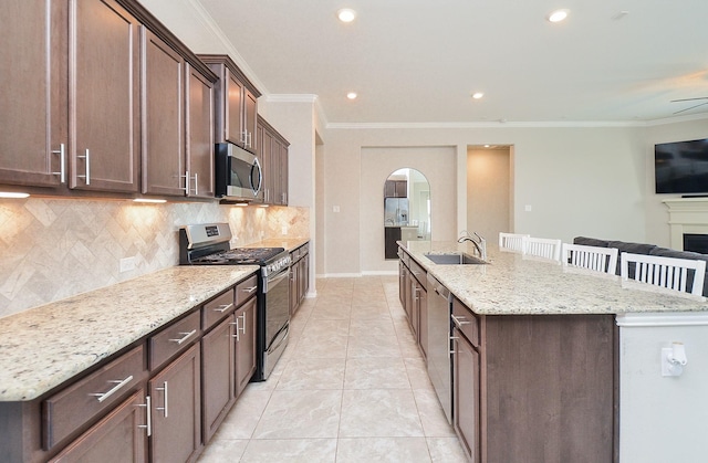 23334 Peareson Bend Ln, Richmond, TX 77469 - kitchen featuring appliances with stainless steel finishes, a large island with sink, arched walkways, backsplash, and crown molding